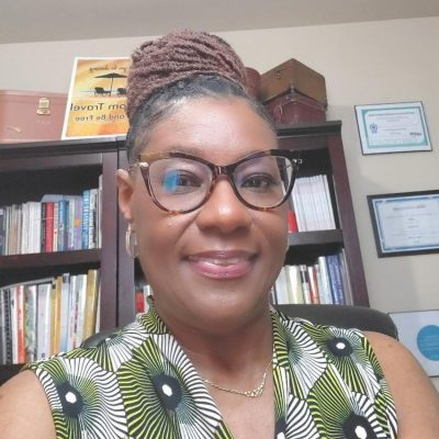 Toni in office with pinned up hair do and green white and black sleeveless top